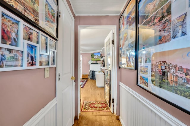 hallway with ornamental molding and light hardwood / wood-style flooring