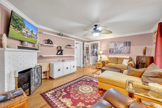 living room featuring ceiling fan, ornamental molding, light wood-type flooring, and a fireplace