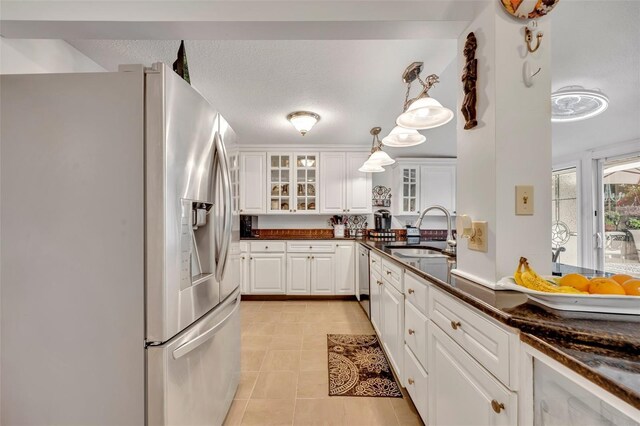 kitchen featuring white cabinets, light tile patterned floors, appliances with stainless steel finishes, sink, and pendant lighting