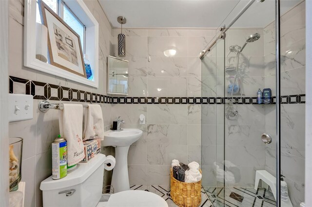 bathroom with tile walls, toilet, and a shower with door