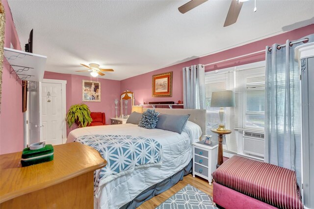 bedroom with a textured ceiling, hardwood / wood-style flooring, and ceiling fan