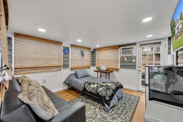 bedroom featuring hardwood / wood-style flooring and a wall mounted air conditioner