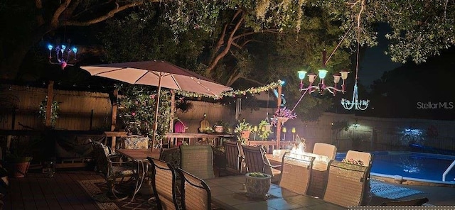 patio at twilight featuring a swimming pool side deck