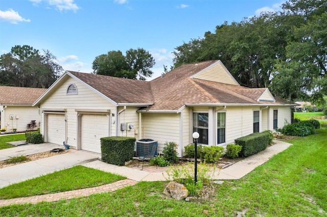 ranch-style home with cooling unit, a garage, and a front lawn