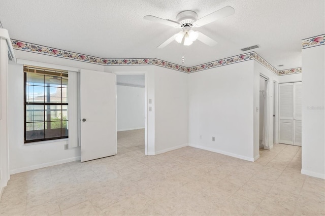 empty room with ceiling fan and a textured ceiling