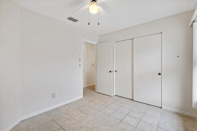 unfurnished bedroom featuring ceiling fan, a textured ceiling, a closet, and light tile patterned floors