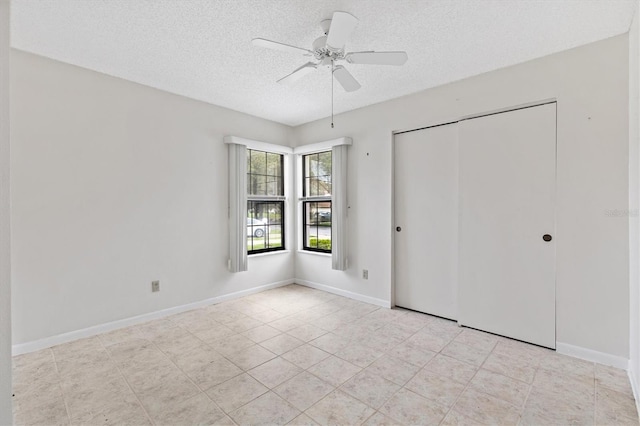 unfurnished bedroom with a textured ceiling, ceiling fan, and a closet