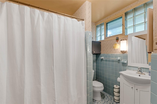 bathroom featuring toilet, tile patterned flooring, vanity, curtained shower, and tile walls