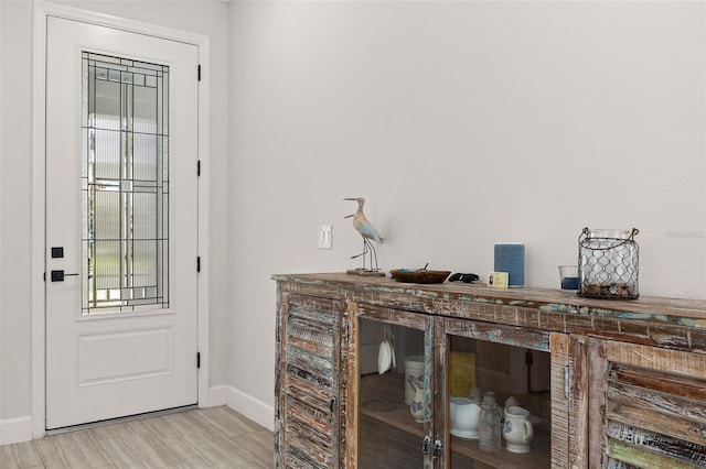 doorway to outside with light hardwood / wood-style floors and indoor bar