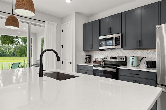 kitchen with gray cabinets, appliances with stainless steel finishes, hanging light fixtures, and sink