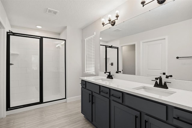 bathroom with vanity, a textured ceiling, and a shower with door