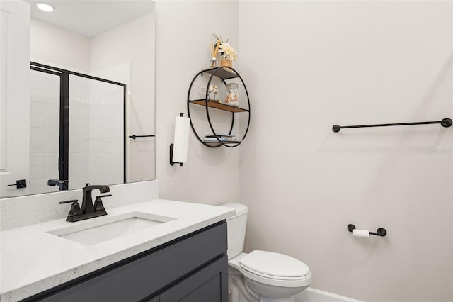 bathroom featuring a shower with door, vanity, and toilet