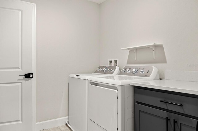 washroom featuring washer and clothes dryer, cabinets, and light hardwood / wood-style floors