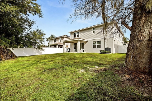 rear view of house featuring a lawn and central AC