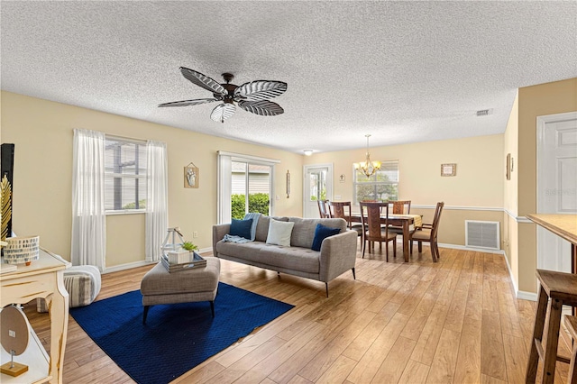 living room with light hardwood / wood-style floors, a textured ceiling, and ceiling fan with notable chandelier