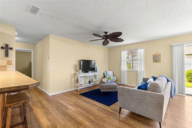 living room with light hardwood / wood-style floors, a textured ceiling, and a wealth of natural light