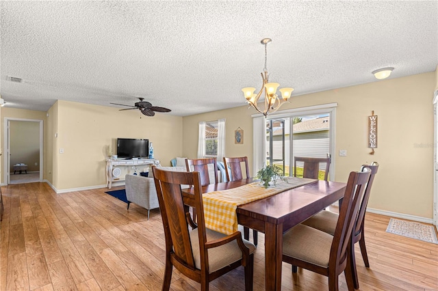 dining space featuring a textured ceiling, ceiling fan with notable chandelier, and light wood-type flooring