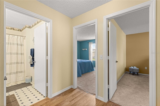 hallway featuring light hardwood / wood-style floors and a textured ceiling