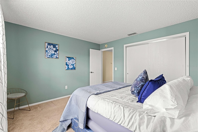 bedroom with light carpet, a textured ceiling, and a closet