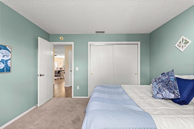 carpeted bedroom featuring a closet and a textured ceiling