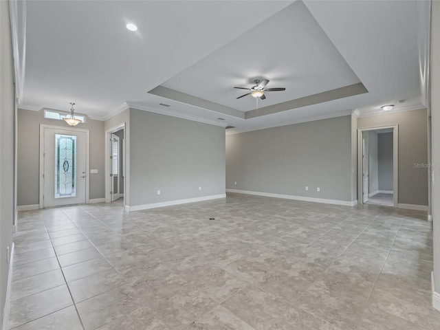 empty room with ceiling fan, a raised ceiling, and ornamental molding