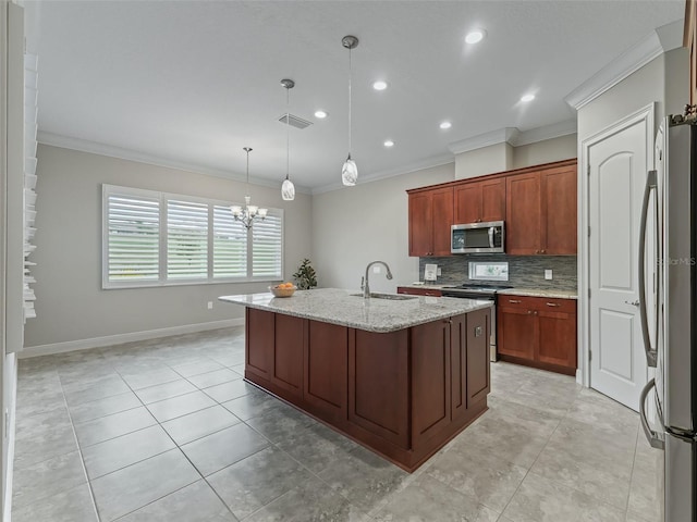 kitchen featuring ornamental molding, stainless steel appliances, sink, decorative light fixtures, and a center island with sink