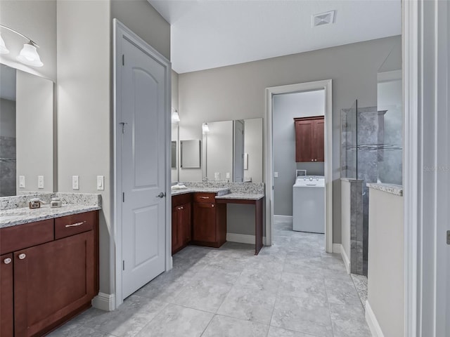 bathroom featuring tile patterned flooring, a tile shower, vanity, and washer / clothes dryer