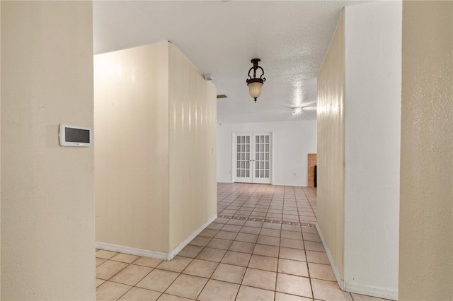 corridor featuring french doors, a textured ceiling, and light tile patterned flooring