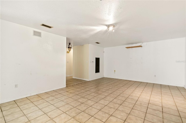 tiled spare room featuring a textured ceiling