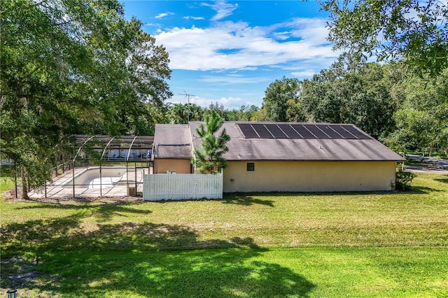 rear view of property with a lawn and solar panels