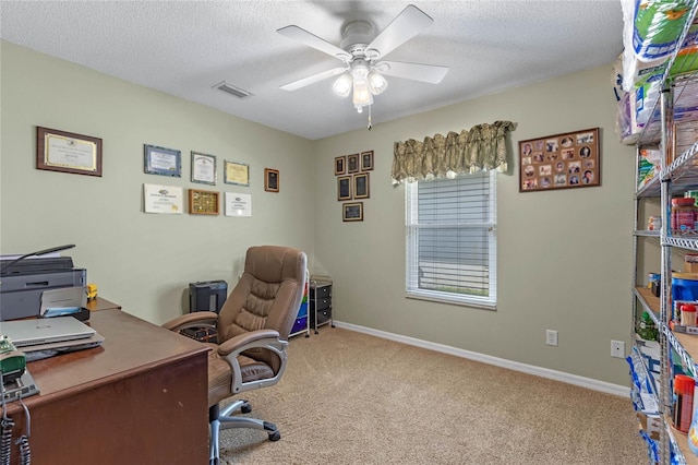 carpeted home office with a textured ceiling and ceiling fan