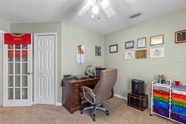 office space featuring a textured ceiling, light colored carpet, and ceiling fan