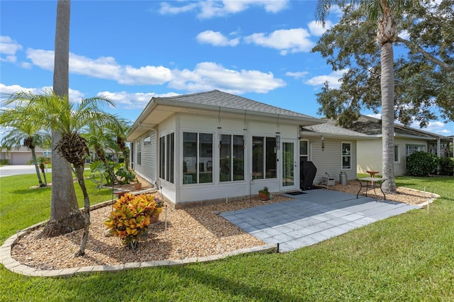 back of property with a lawn, a patio area, and a sunroom