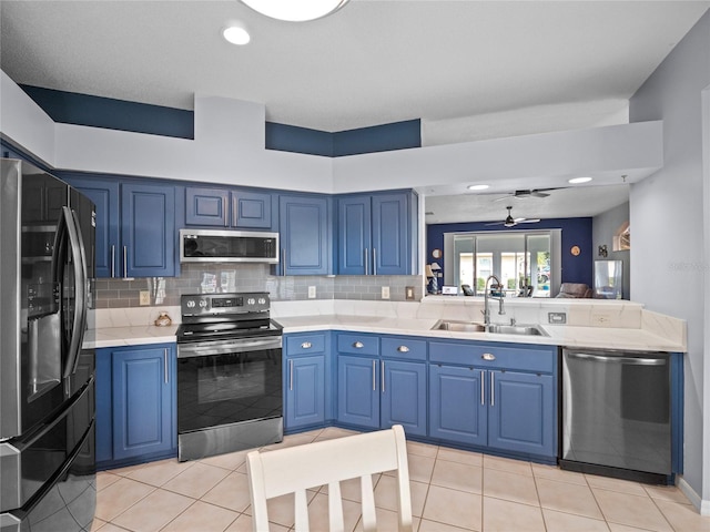 kitchen with sink, blue cabinets, ceiling fan, tasteful backsplash, and appliances with stainless steel finishes