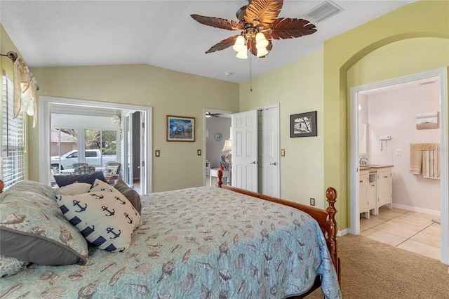 bedroom featuring a textured ceiling, lofted ceiling, connected bathroom, light carpet, and ceiling fan