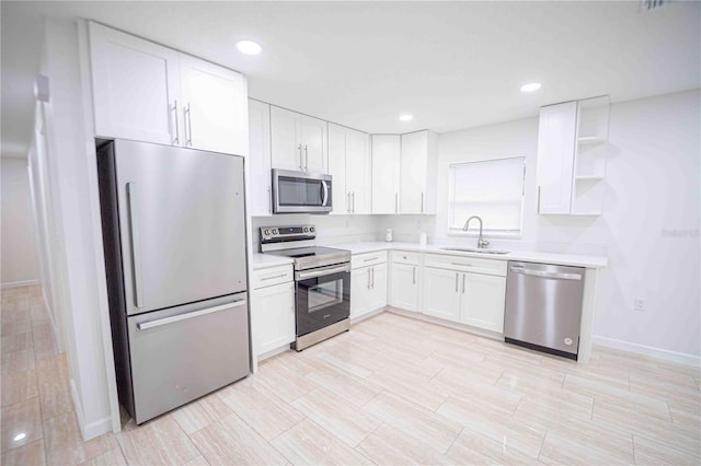 kitchen featuring white cabinetry, stainless steel appliances, a sink, and light countertops