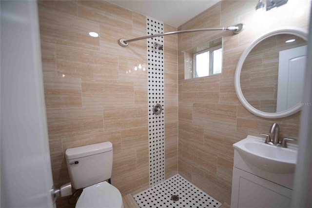 bathroom featuring tiled shower, vanity, and tile walls