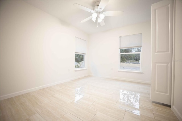 spare room featuring ceiling fan and baseboards