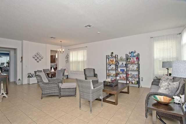 living room with a textured ceiling, a healthy amount of sunlight, light tile patterned flooring, and a notable chandelier