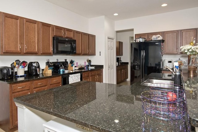 kitchen featuring dark stone countertops, sink, and black appliances