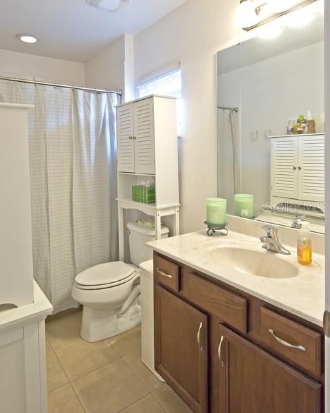 bathroom with curtained shower, tile patterned flooring, vanity, and toilet