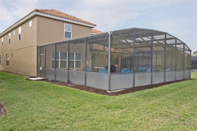 rear view of house featuring a lawn and glass enclosure