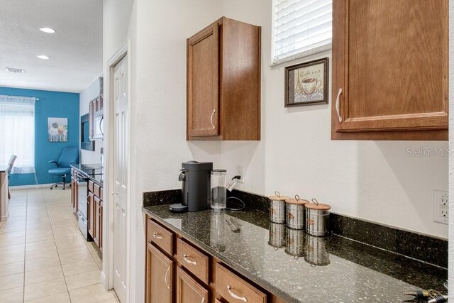 436 Orange Cosmos Blvd, Davenport, FL 33837 - kitchen featuring dark stone counters, brown cabinetry, light tile patterned flooring, range with electric stovetop, and recessed lighting