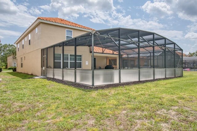 436 Orange Cosmos Blvd, Davenport, FL 33837 - back of property with a lawn, stucco siding, a tile roof, and glass enclosure