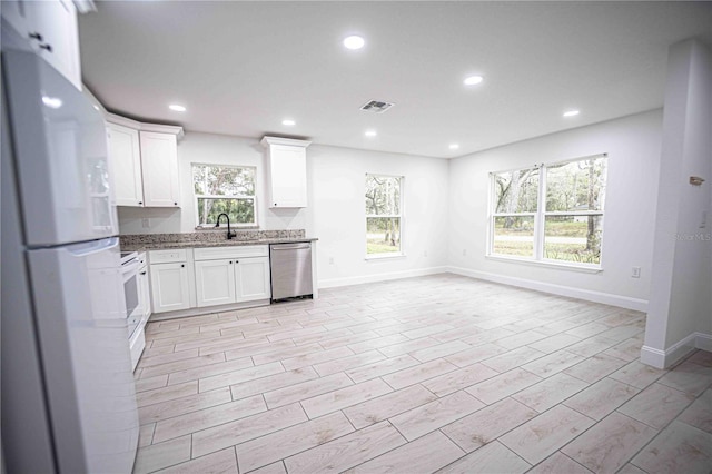 kitchen with visible vents, freestanding refrigerator, a healthy amount of sunlight, white cabinets, and dishwasher