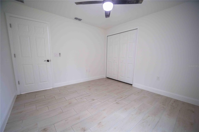 unfurnished bedroom with baseboards, visible vents, light wood-style flooring, ceiling fan, and a closet