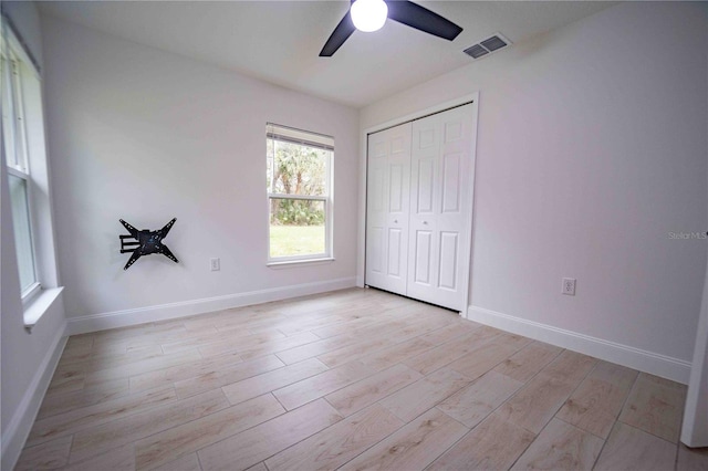 unfurnished bedroom with light wood-style floors, a closet, visible vents, and baseboards