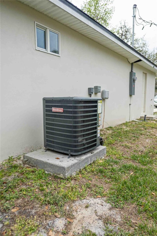 exterior details with stucco siding, electric meter, and central air condition unit