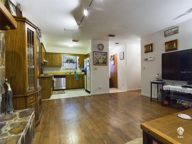 kitchen featuring dishwasher, light hardwood / wood-style floors, white fridge, and rail lighting