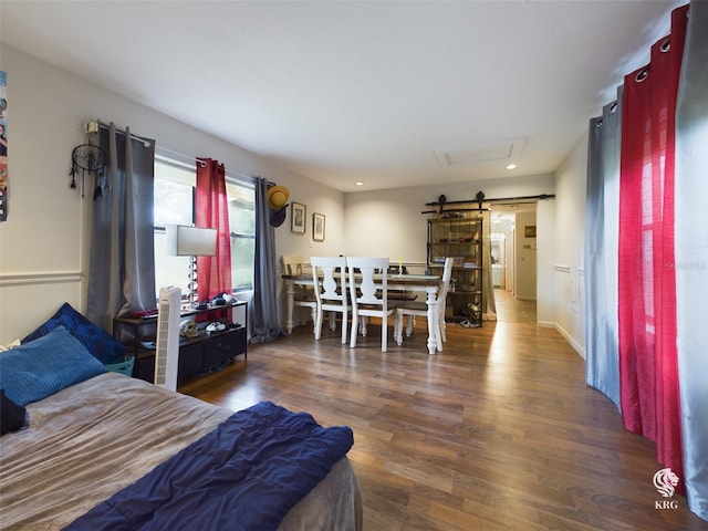 bedroom featuring a barn door and dark wood-type flooring